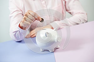 Hand putting coin into piggy bank closeup. Selective focus