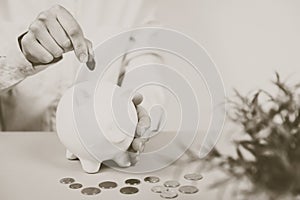 Hand putting coin into piggy bank closeup. Selective focus