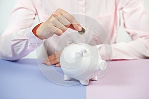 Hand putting coin into piggy bank closeup. Selective focus