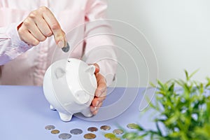 Hand putting coin into piggy bank closeup. Selective focus