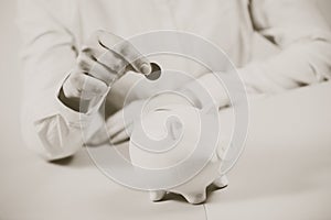 Hand putting coin into piggy bank closeup. Selective focus