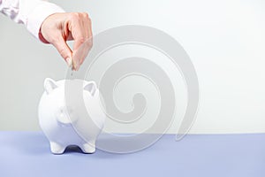 Hand putting coin into piggy bank closeup. Selective focus