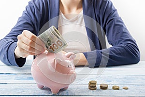 Hand putting coin into piggy bank closeup. selective focus