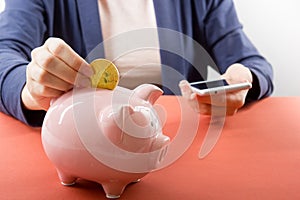 Hand putting coin into piggy bank closeup. selective focus