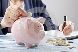 Hand putting coin into piggy bank closeup. selective focus