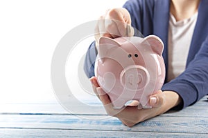 Hand putting coin into piggy bank closeup. selective focus