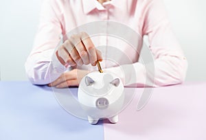 Hand putting coin into piggy bank closeup. Selective focus