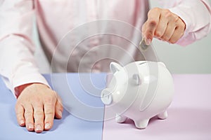 Hand putting coin into piggy bank closeup. Selective focus