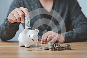 Hand putting coin on piggy bank for money saving concept
