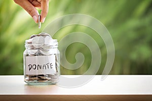 The Hand putting Coins in glass jar for giving and donation concept