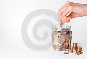 Hand putting coins in glass jar. Money saving concept