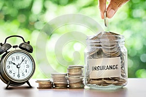 Hand putting Coins in glass jar for money saving insurance concept