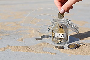 Hand putting Coins in glass jar with SAVE label