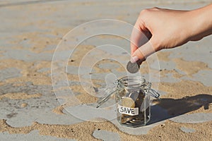 Hand putting Coins in glass jar with SAVE label