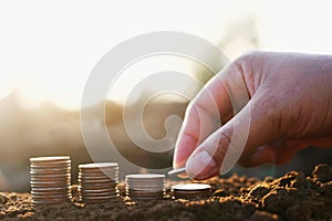 hand putting coins stack on soil. saving money accounting finance concept