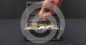 Hand putting coins into treasure chest slow motion footage