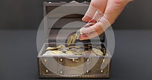 Hand putting coins into treasure chest slow motion footage