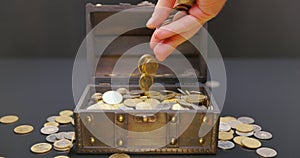 Hand putting coins into treasure chest slow motion footage