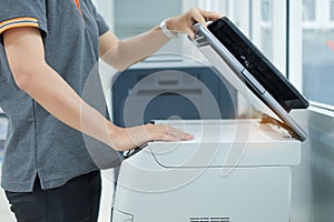 Hand putting a document paper into printer scanner or laser copy machine in office