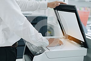 Hand putting a document paper into printer scanner or laser copy machine in office