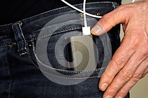 Hand putting external battery pack in jeans pocket