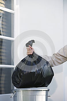 Hand Putting Garbage Bag Into Trash Can