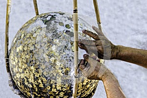 Hand putting gold leaf on boundary stone