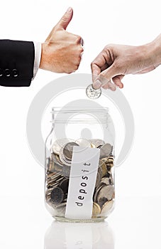 Hand putting Golden coins and seed in clear jar over white background