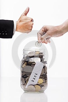 Hand putting Golden coins and seed in clear jar over white background