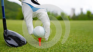 Hand putting golf ball on tee in golf course