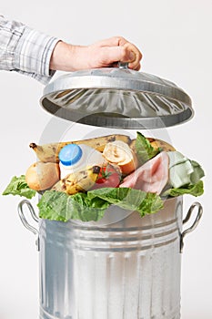 Hand Putting Lid On Garbage Can Full Of Waste Food