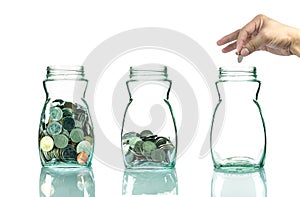 Hand putting mix coins in clear blottle on white background