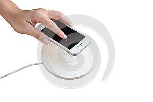 Hand putting mobile phone on wireless charger, modern equipment,