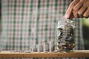 Hand putting money coins in grass bottle