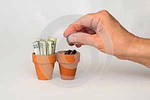 Hand putting money coins in a terracotta pot