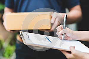 hand putting signature in clipboard to receive package from delivery man