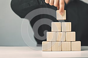 Hand putting and stacking blank wooden cubes on table with copy space for input wording or infographic icon