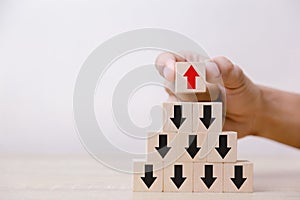 Hand putting wood cube block on top pyramid wooden blocks