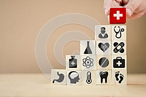 Hand putting wooden cubes stacking of healthcare medicine and hospital icon on table. Health care insurance business and