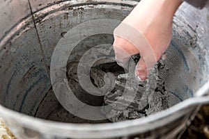 Hand with putty knife in bucket of plaster