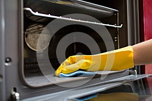 Hand with rag cleaning oven at home kitchen