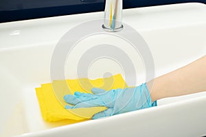 Hand with a rag washes the sink in the bathroom, professional cleaning service