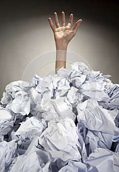 Hand reaches out from heap of papers