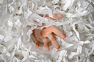 Hand reaches out from heap of shredded paper