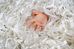 Hand reaches out from heap of shredded paper