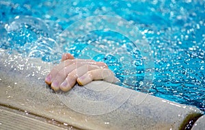 Hand reaches out of a swimming pool