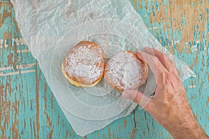 Hand reaches for sweet sugary donut on rustic table