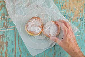 Hand reaches for sweet sugary donut on rustic table photo