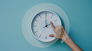 hand reaching out to a white wall clock on a light blue background, seemingly to adjust the time..AI generated image