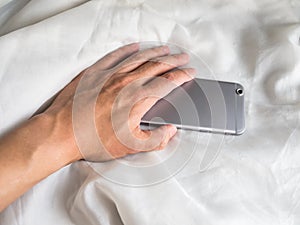 Hand reaching for phone in the bed